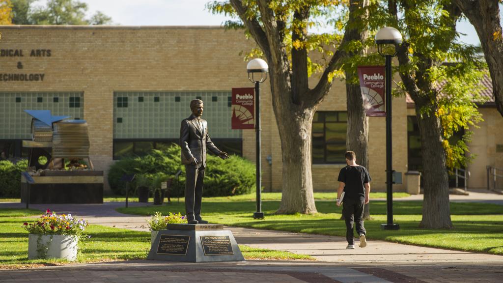 student walking past Hoag statue in Pueblo campus courtyard