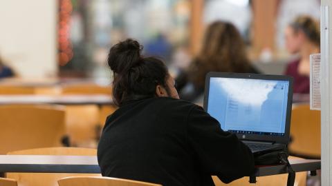 back of student looking at laptop