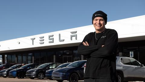 Andrew Gomez-Wormington standing in front of TESLA auto bay