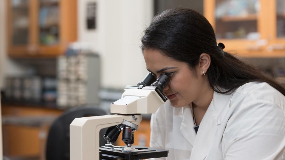 female looking into microscope