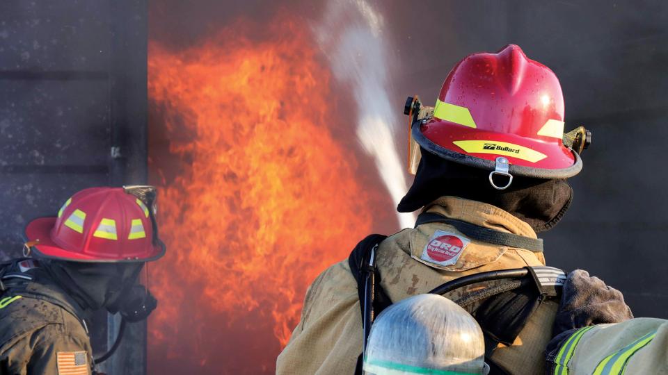 Two Fire Science students putting out a fire during a drill