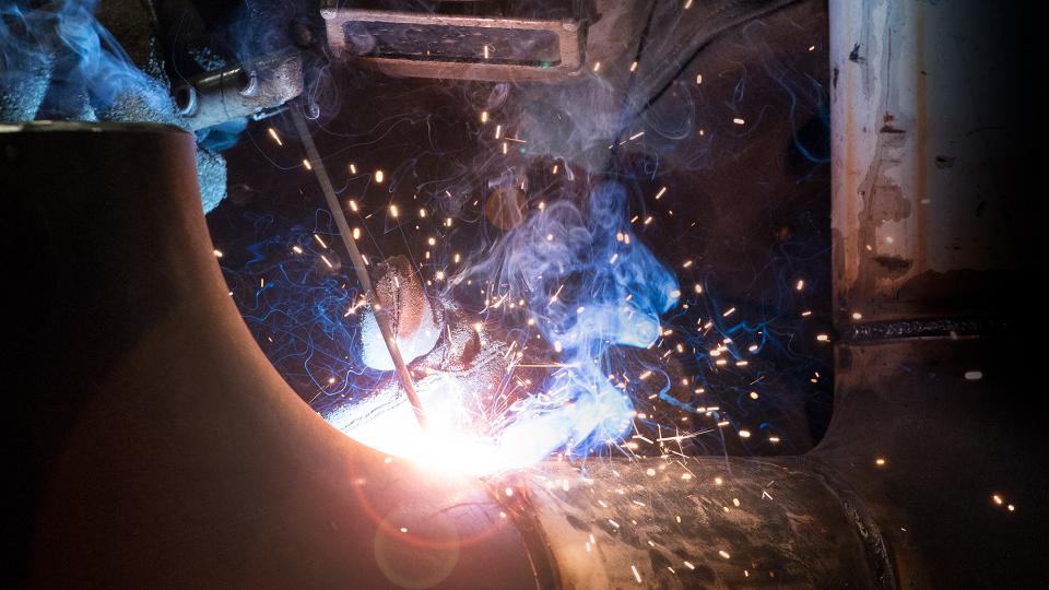 welding student surrounded by colorful welding sparks and smoke