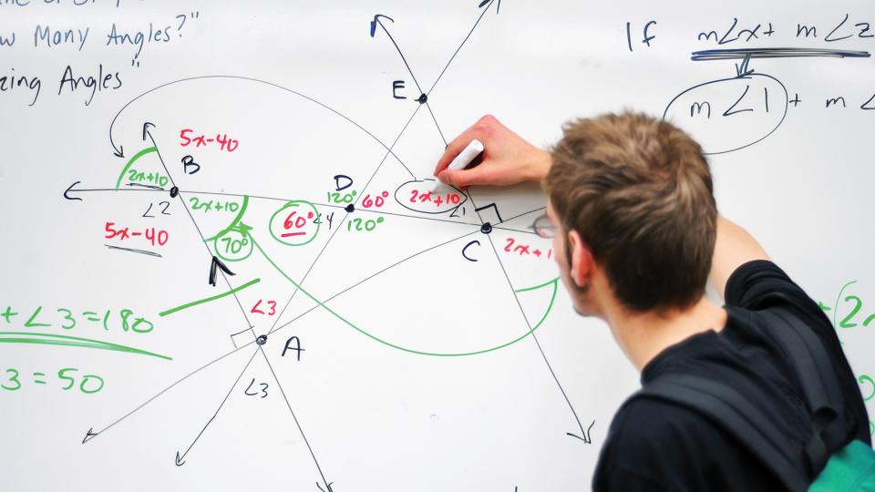 student writing math equations on whiteboard