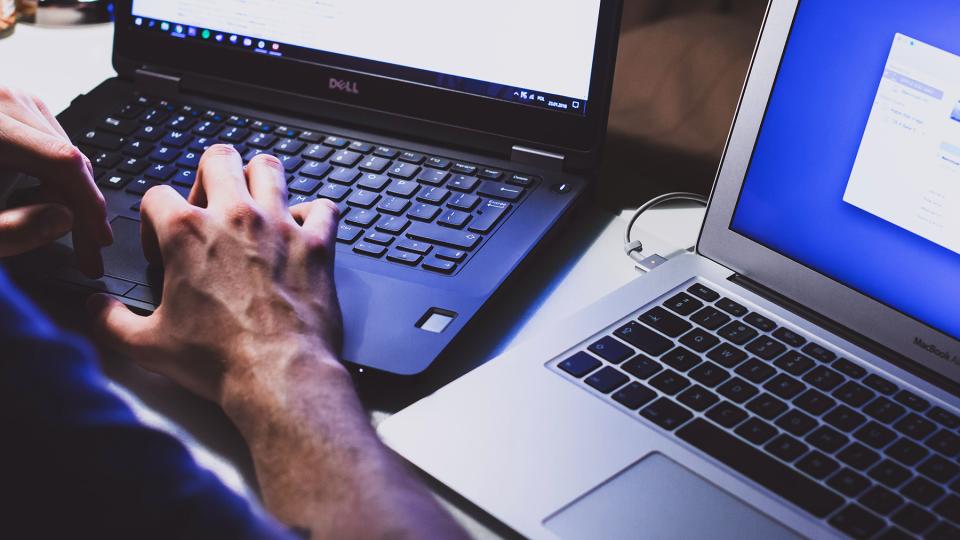 hands working at two different computers