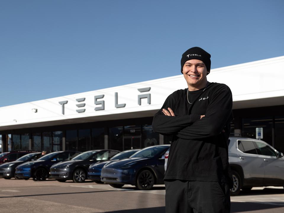 Andrew Gomez-Wormington standing in front of TESLA auto bay
