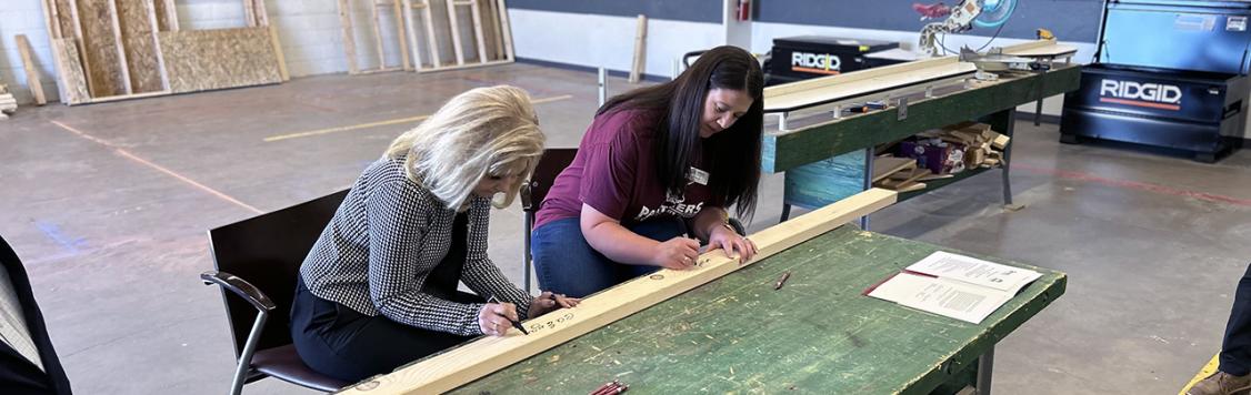 (l-r): Pueblo Community College President Patty Erjavec and Heidi Mitchell, executive director of Habitat for Humanity of Montezuma County, sign a two-by-four that will be used by PCC Southwest students to build a Habitat for Humanity home.