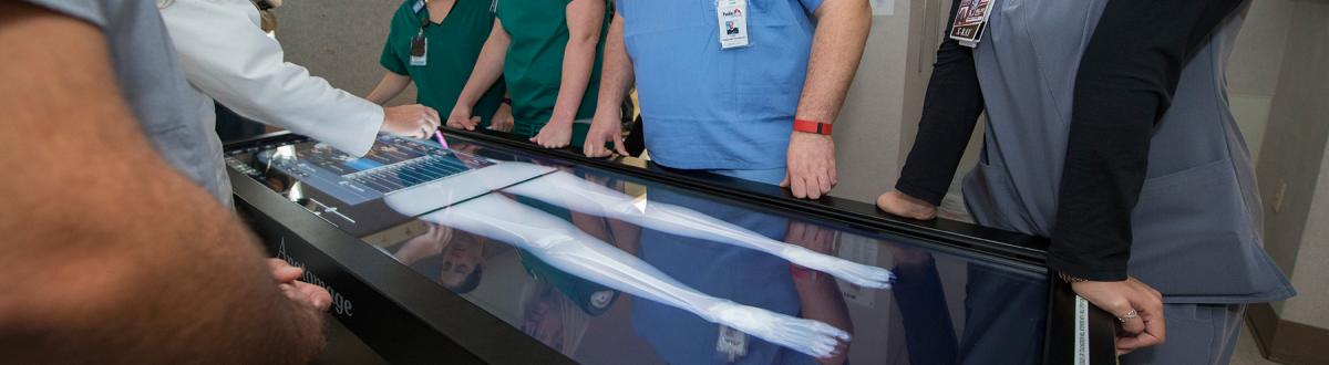 students standing around 3D anatomy visualization system (Anatomage)