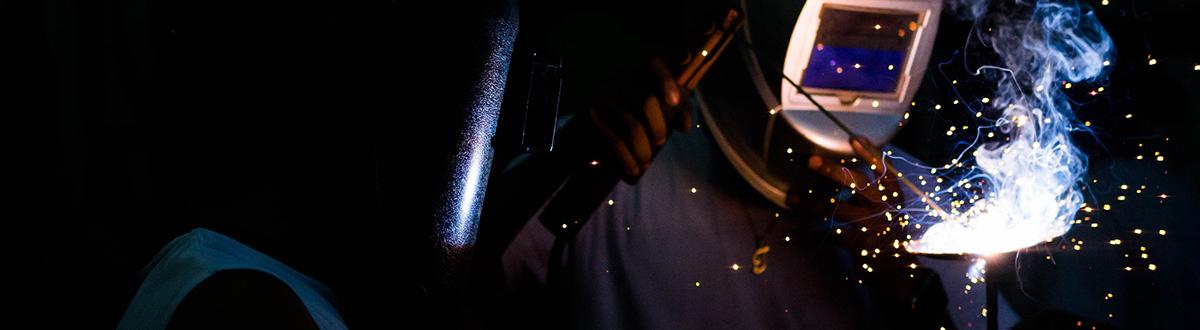 Dark photo of welder with blue flame