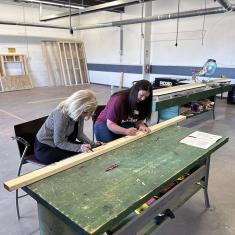 (l-r): Pueblo Community College President Patty Erjavec and Heidi Mitchell, executive director of Habitat for Humanity of Montezuma County, sign a two-by-four that will be used by PCC Southwest students to build a Habitat for Humanity home.