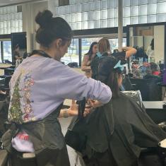 Cosmetology student cutting young girl's hair