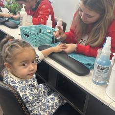 Cosmetology student painting young girl's nails